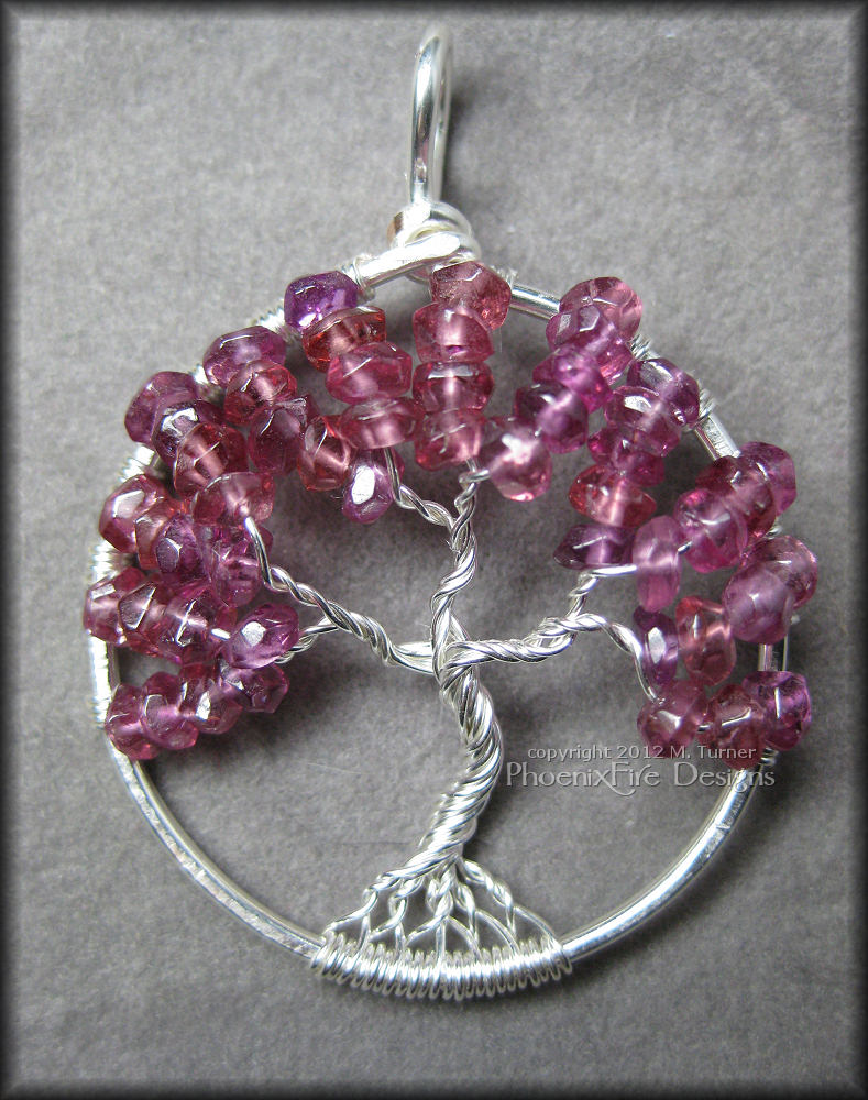 rhodolite-garnet-tol1a Stunning, semi-precious Rhodolite Garnet rondelles in a bright raspberry pink color are set in sterling silver wire to form a beautiful Tree of Life pendant.